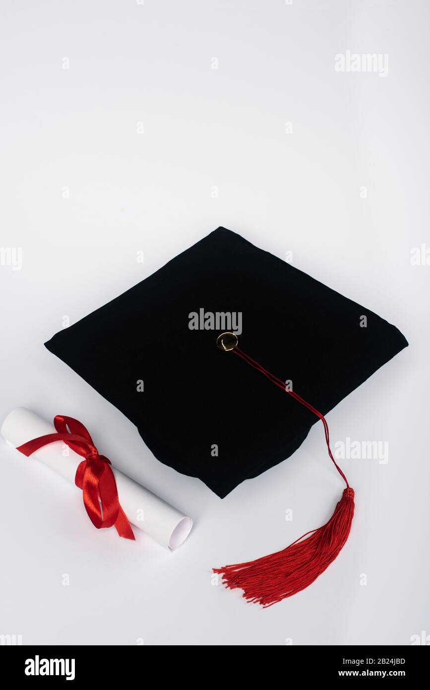 Black graduation cap with red tassel and diploma on white background