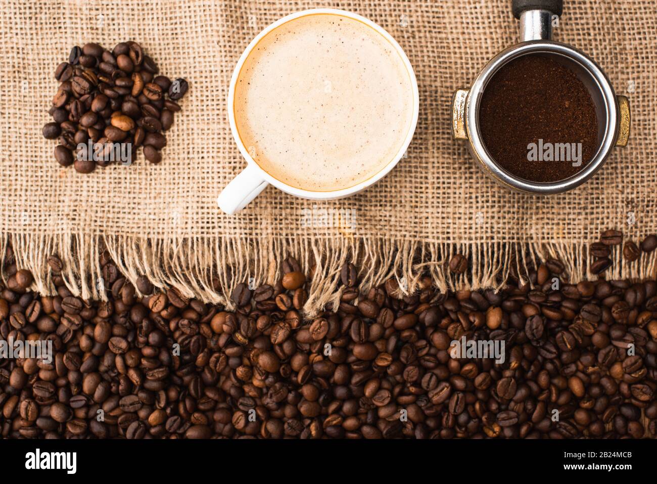 top view of fresh roasted coffee beans and sackcloth with cappuccino
