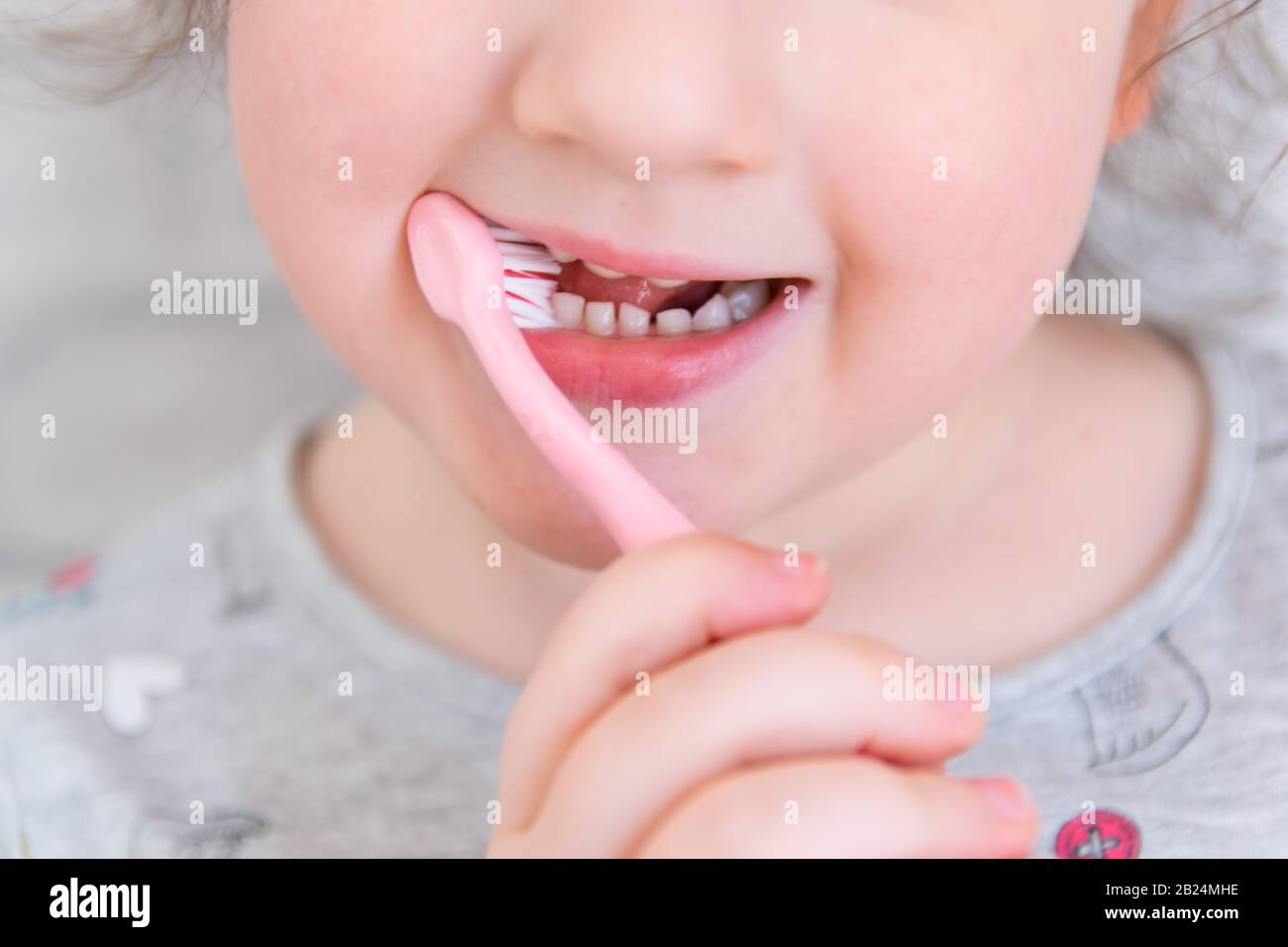 Cute little child in bathroom cleaning the teeth with pink brush. Stock Photo