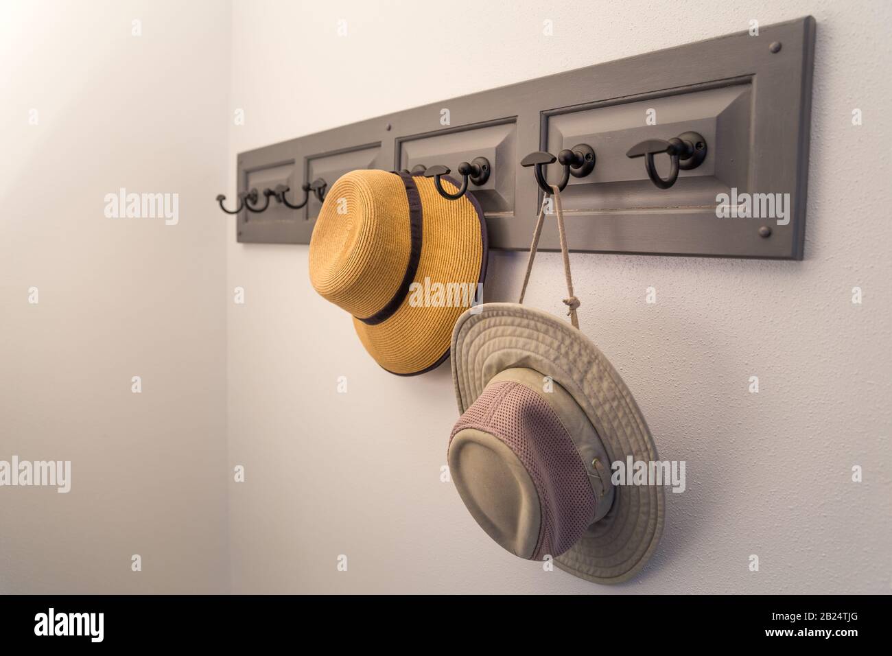 Two hats hanging on a coat rack, view from the side. No people. Horizontal picture. Stock Photo