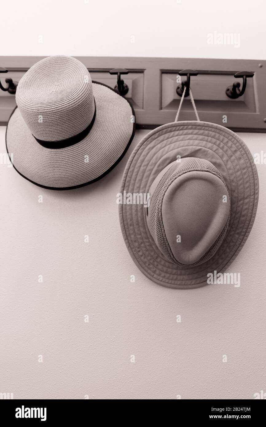 Sepia toned picture of two hats hanging on a rack on a wall. Vertical. No people. Stock Photo