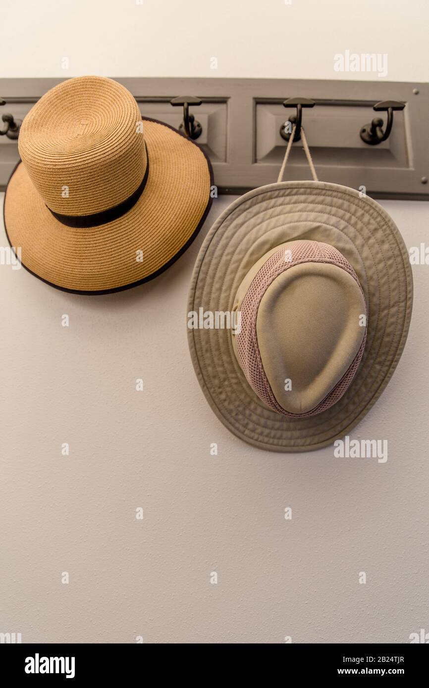Vertical picture of two hats hanging on a rack on a wall. No people Stock Photo