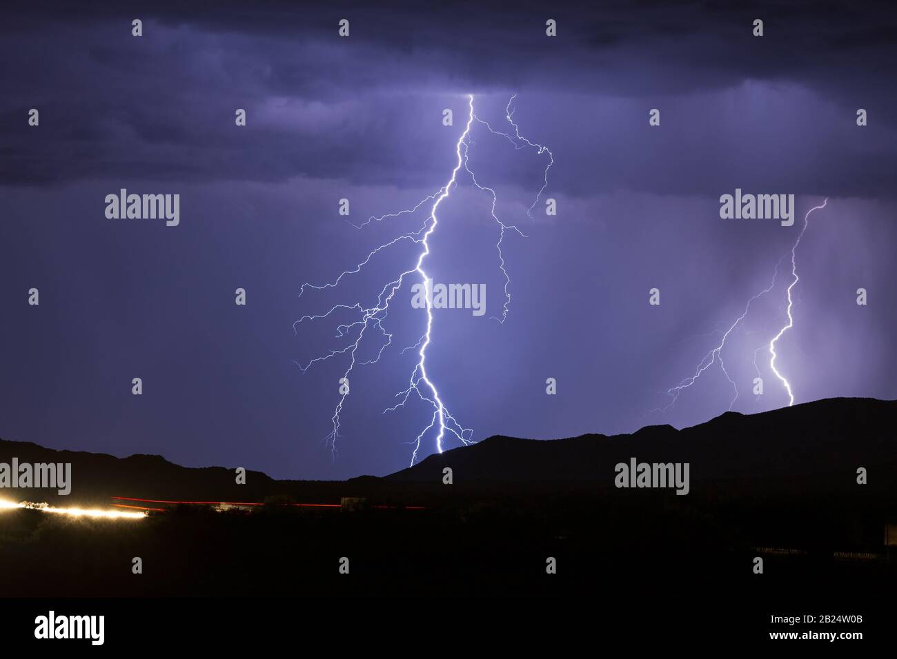 Night sky with a forked lightning strike hitting a mountain in a thunderstorm near Phoenix, Arizona Stock Photo