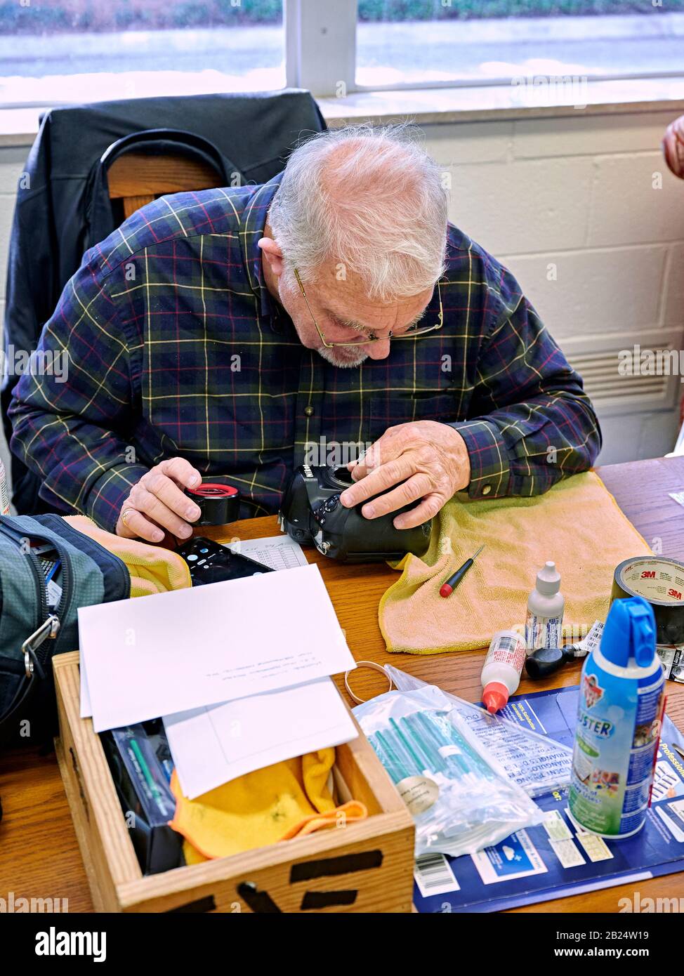 Mature older man, technician, inspecting and cleaning a modern dslr camera or mirrorless camera sensor in Montgomery Alabama, USA. Stock Photo