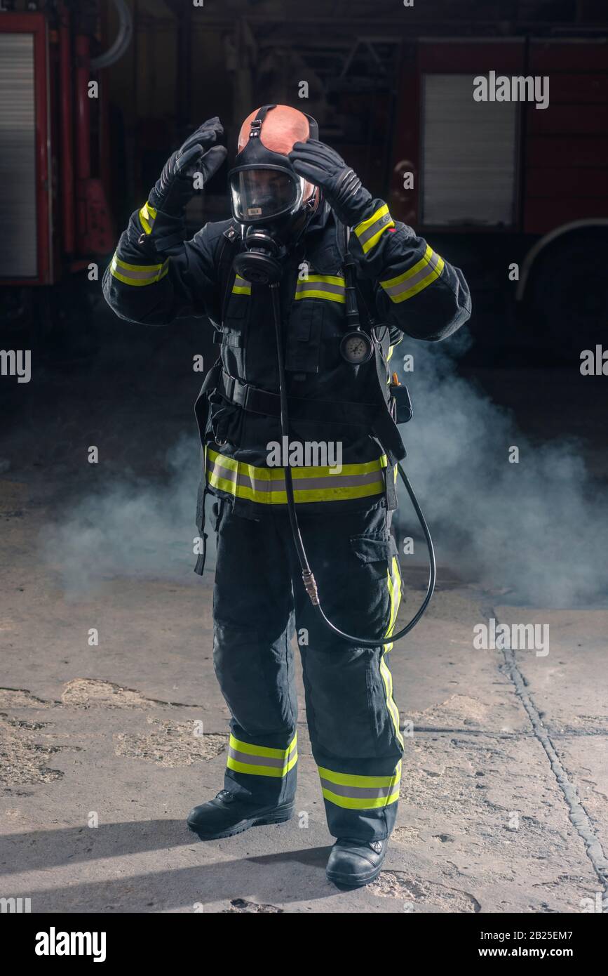 Portrait of a fireman wearing firefighter turnouts and helmet. Dark ...