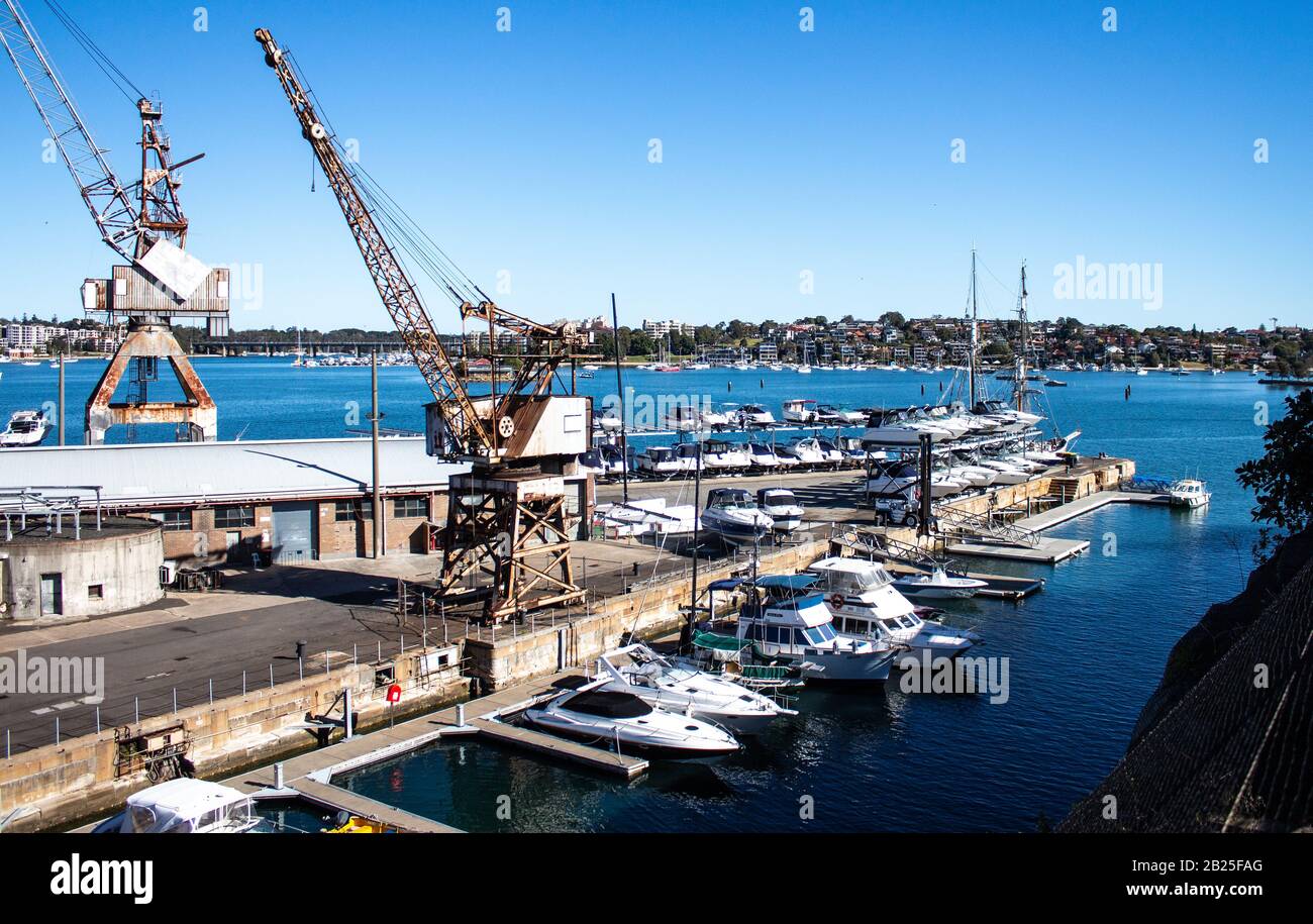 Dockyard wharf working shipyard on harbour with cranes, boats, clear blue sky Stock Photo