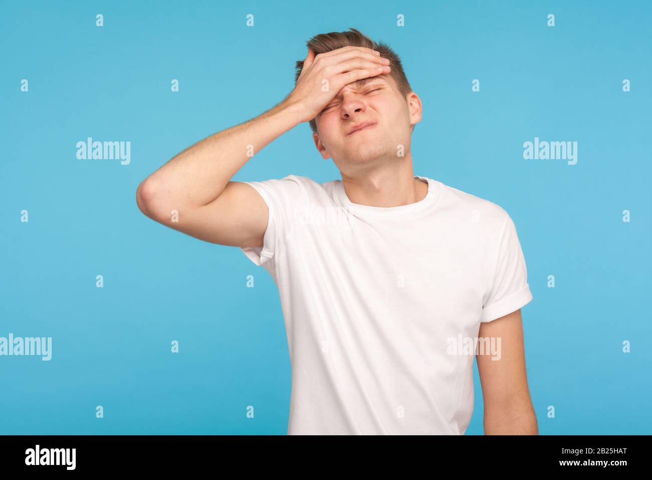 Oh no, I forgot! Portrait of unlucky man in casual white t-shirt making facepalm gesture, feeling regret and shame about forgotten event, bad memory. Stock Photo