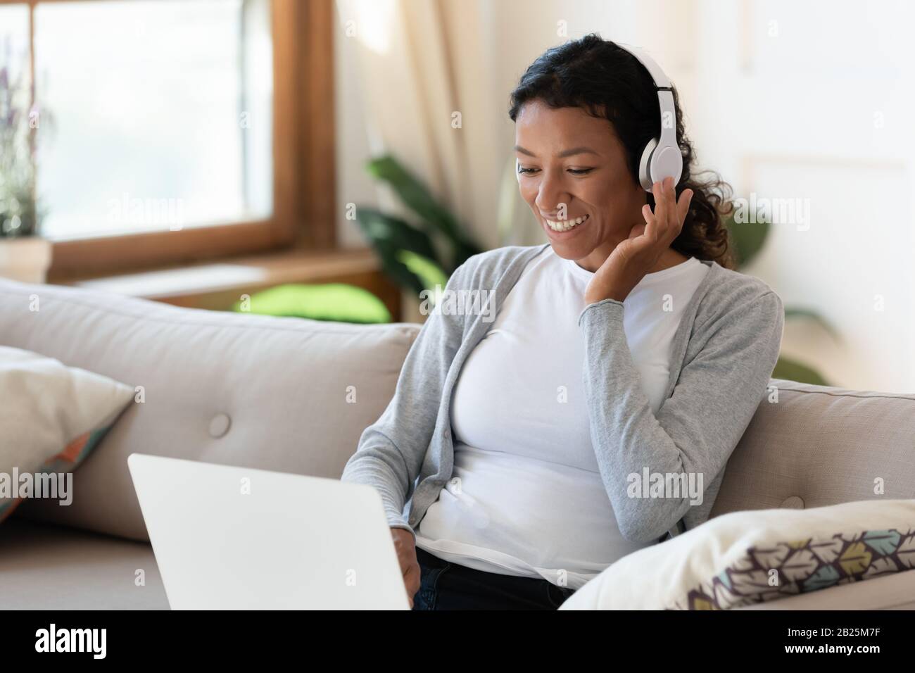 Happy biracial woman watch webinar in headphones at home Stock Photo