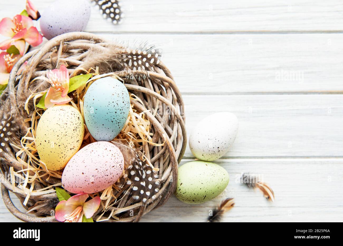 Easter background with colorful eggs in nest on a white wooden ...
