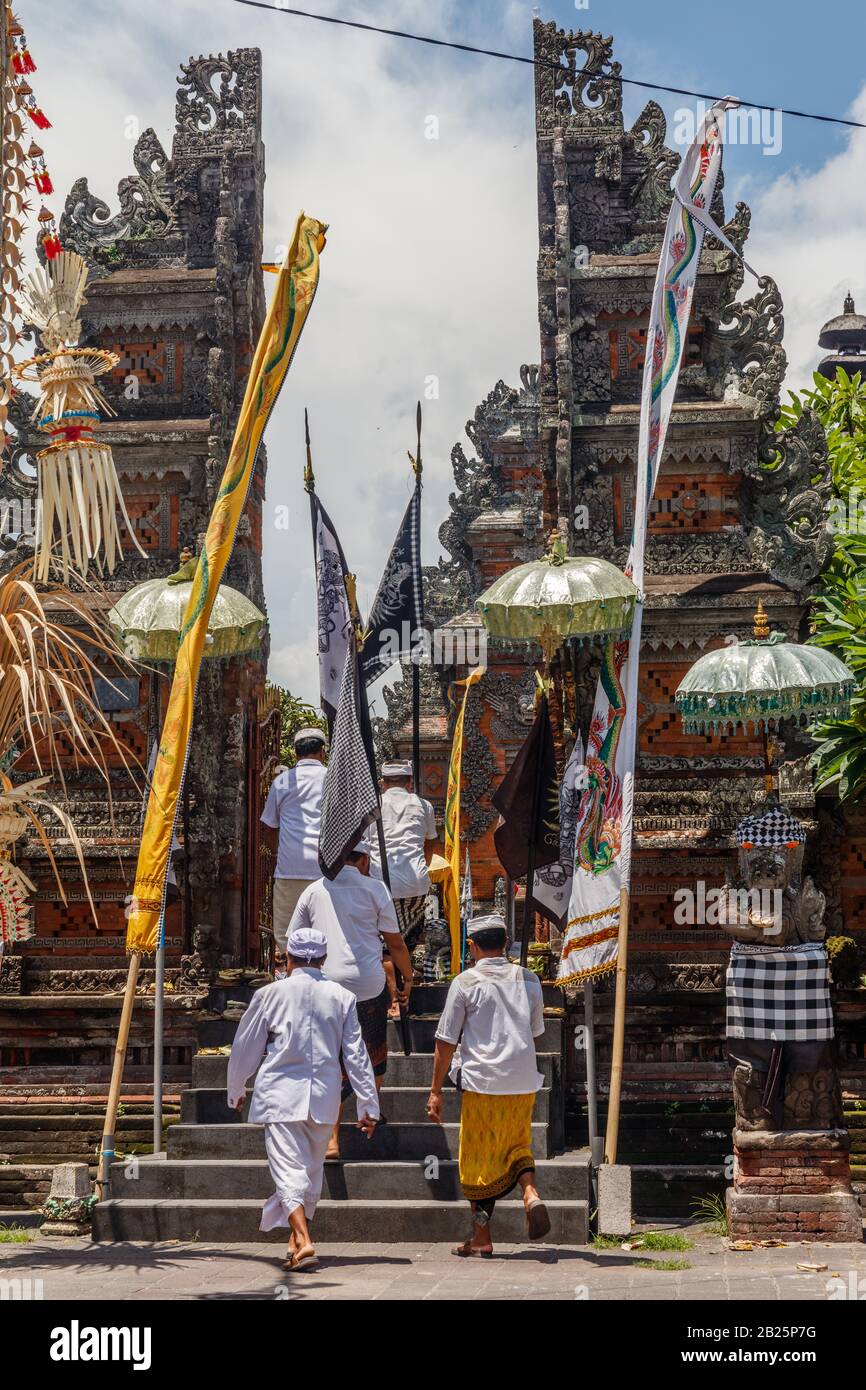 People walking into a Balinese Hindu temple during Kuningan celebration. Munggu village, Bali, Indonesia. Vertical image. Stock Photo