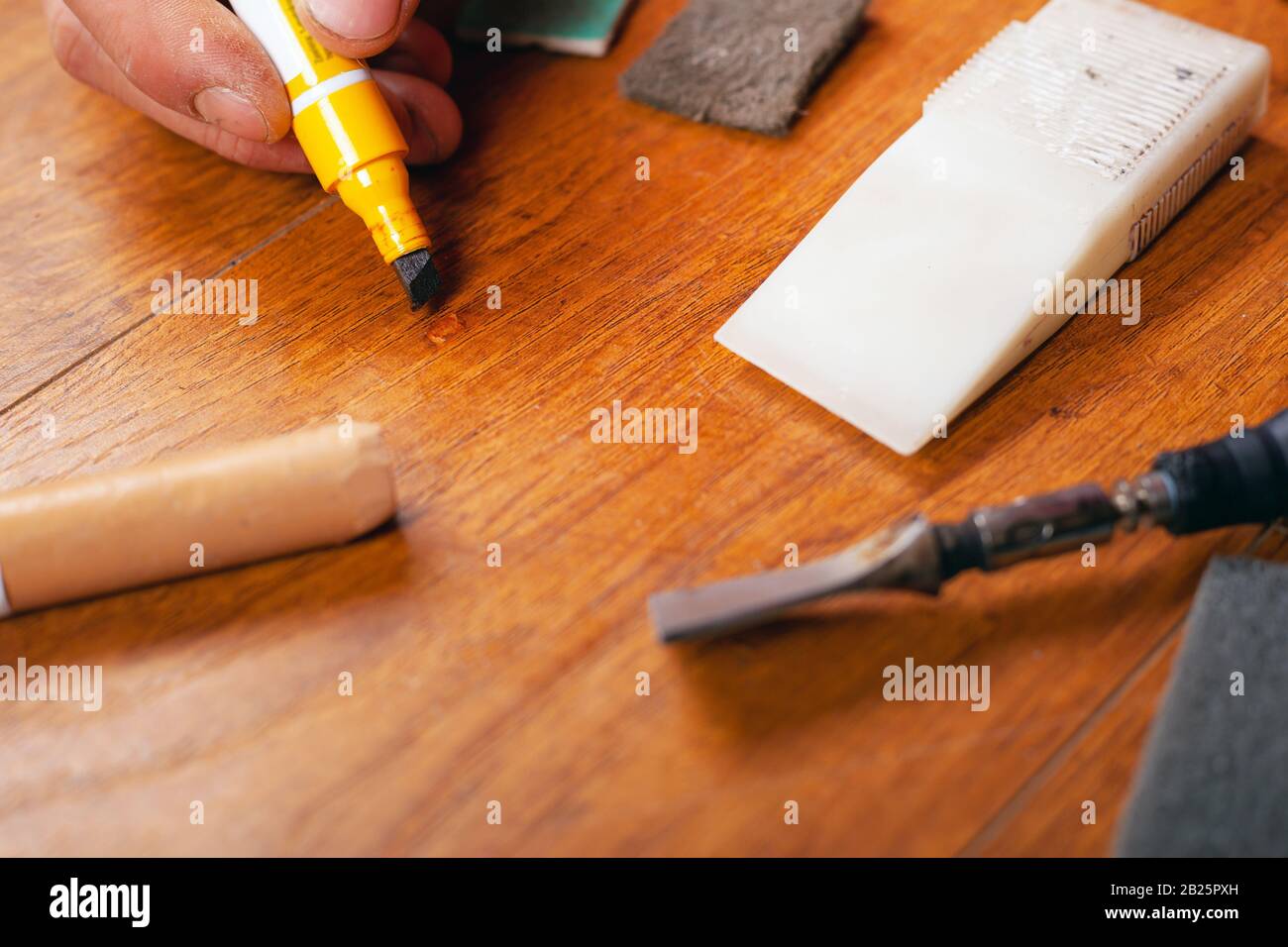 repair restoration laminate flooring parquet and wood products.sealing scratches and chips. master processes the surface with a special pencil to remo Stock Photo