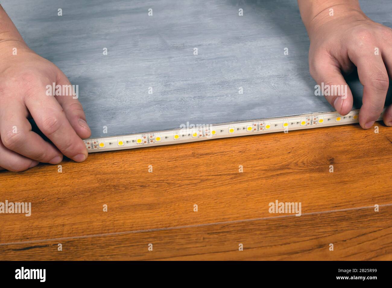worker installs strip LED lighting. installation of decorative diode tape. Stock Photo