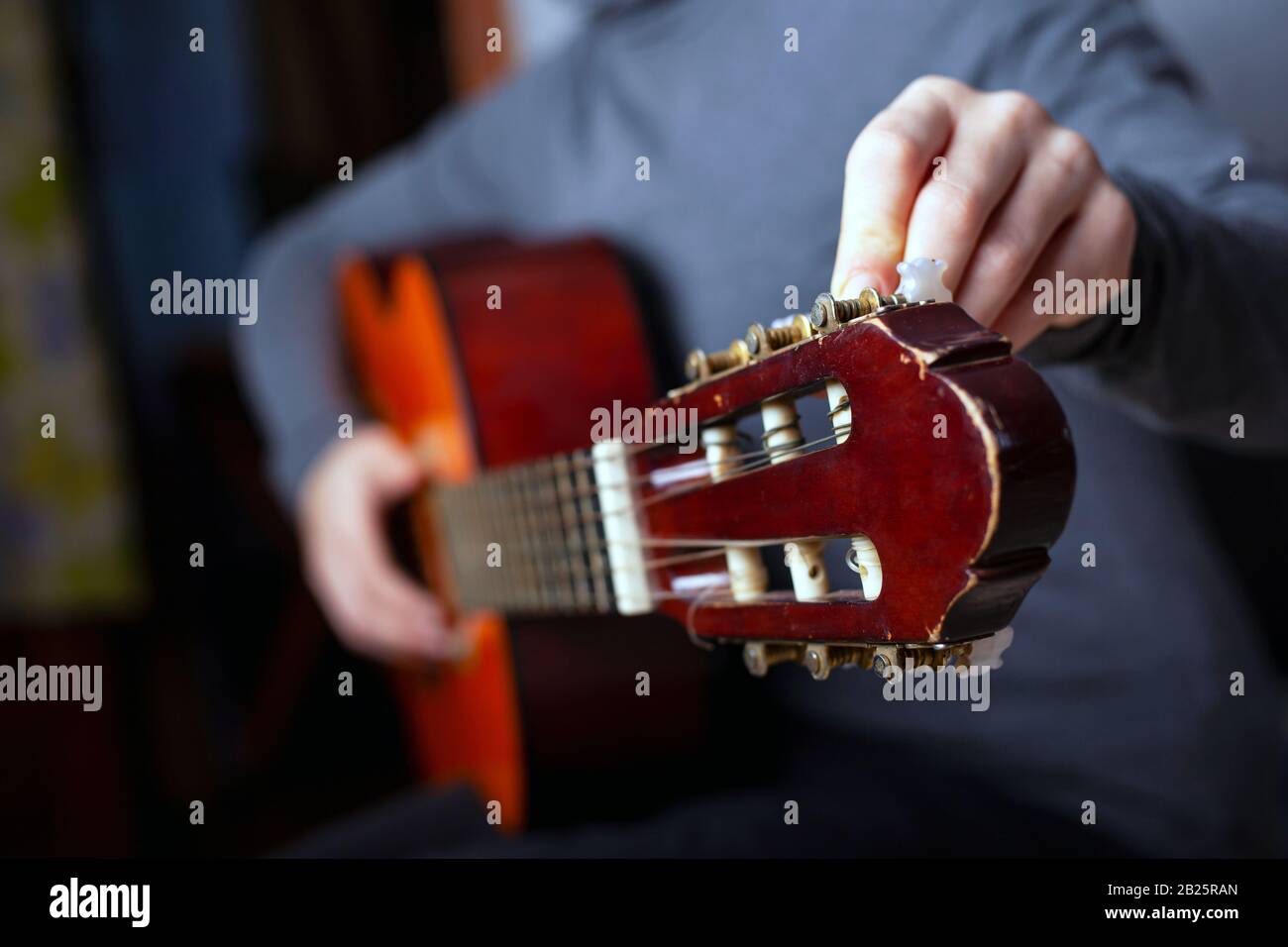 The musician tunes an acoustic six-string guitar. Stock Photo