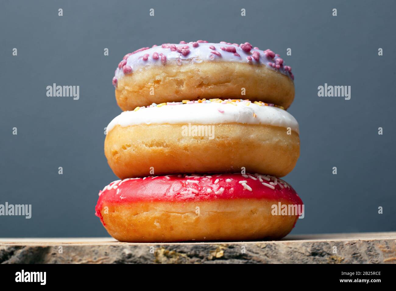 three donuts with colored glaze of violet red and white with powder ...