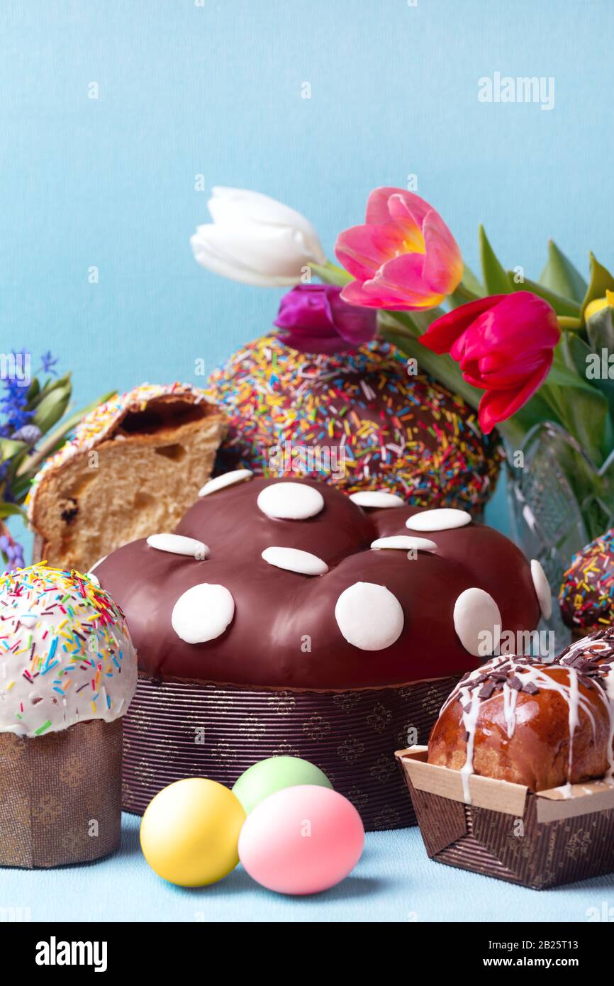easter cakes and spring flowers, easter bread and eggs over blue background Stock Photo