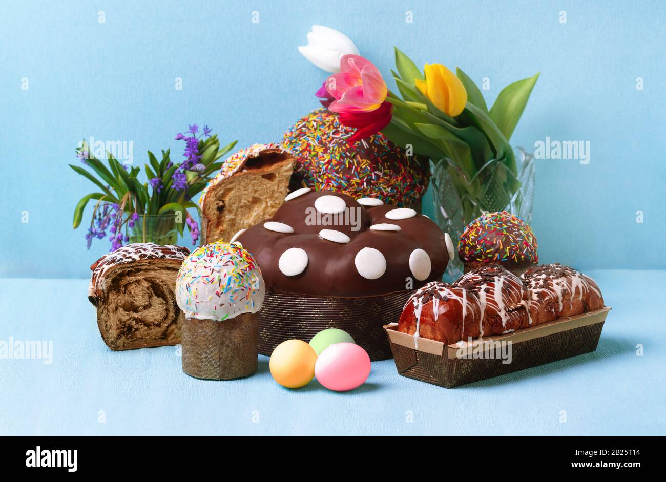 easter cakes and spring flowers, easter bread and eggs over blue background Stock Photo