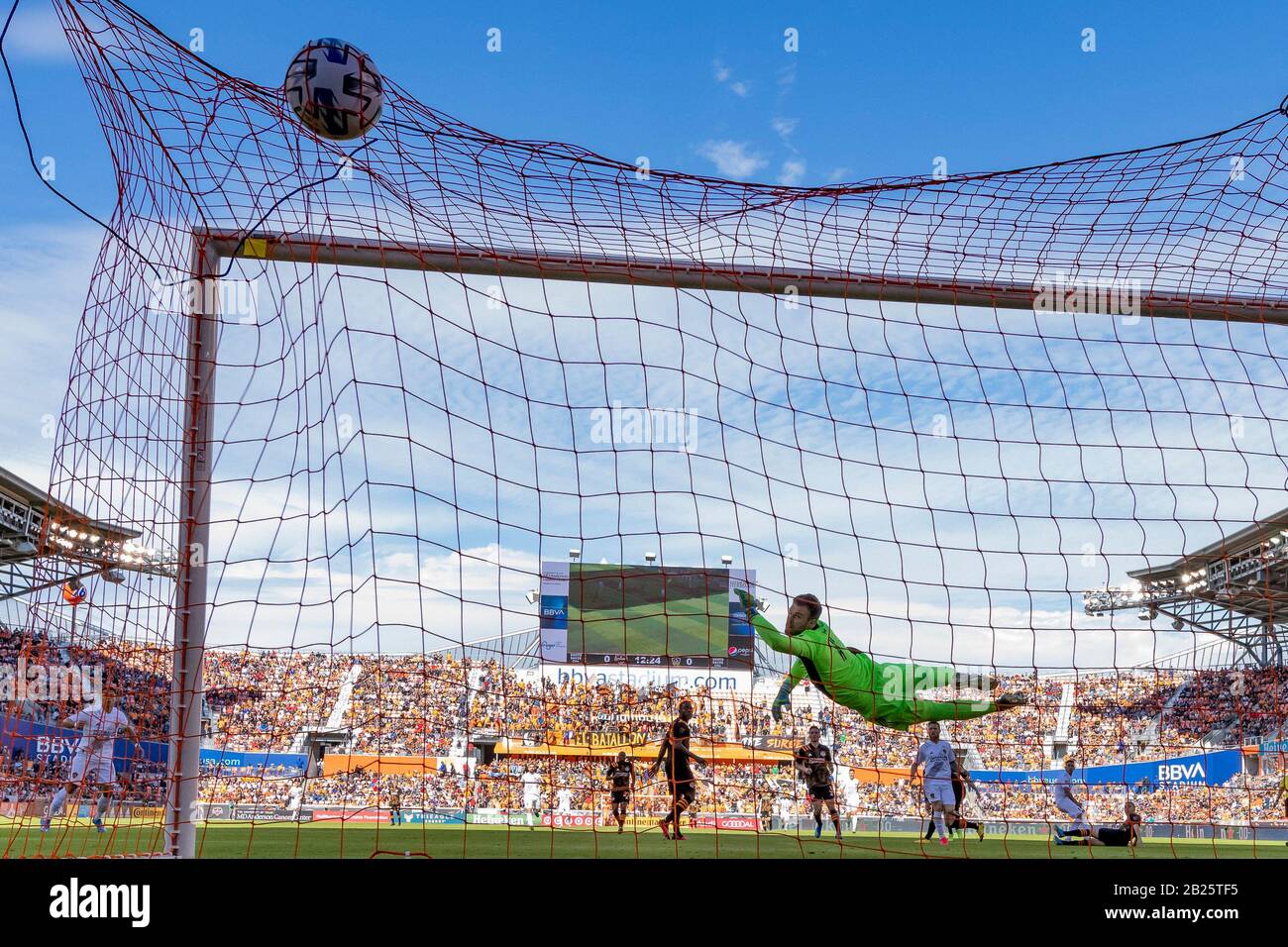 Houston, Texas, USA. 29th Feb, 2020. Los Angeles Galaxy forward Cristian Pavon (10) takes the shot and scores as Houston Dynamo goalkeeper Marko Maric (1) jumps up for the save but the ball is just out of reach at BBVA Stadium in Houston, Texas. Maria Lysaker/CSM/Alamy Live News Stock Photo