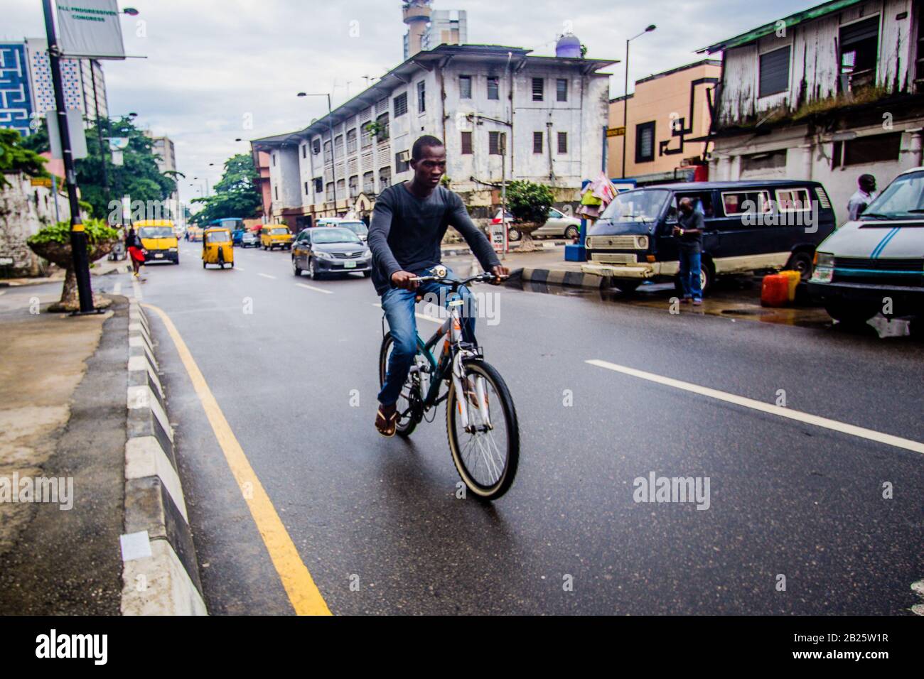 a man riding a bike on a street in Lagos, Nigeria. Stock Photo