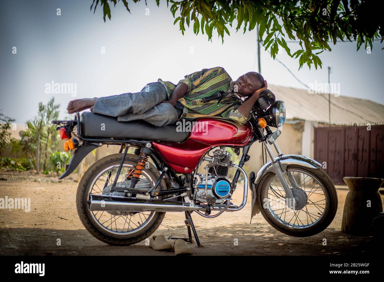 Motorcycle taxi (okada) drivers take a nap on their bikes in Nigeria. Stock Photo