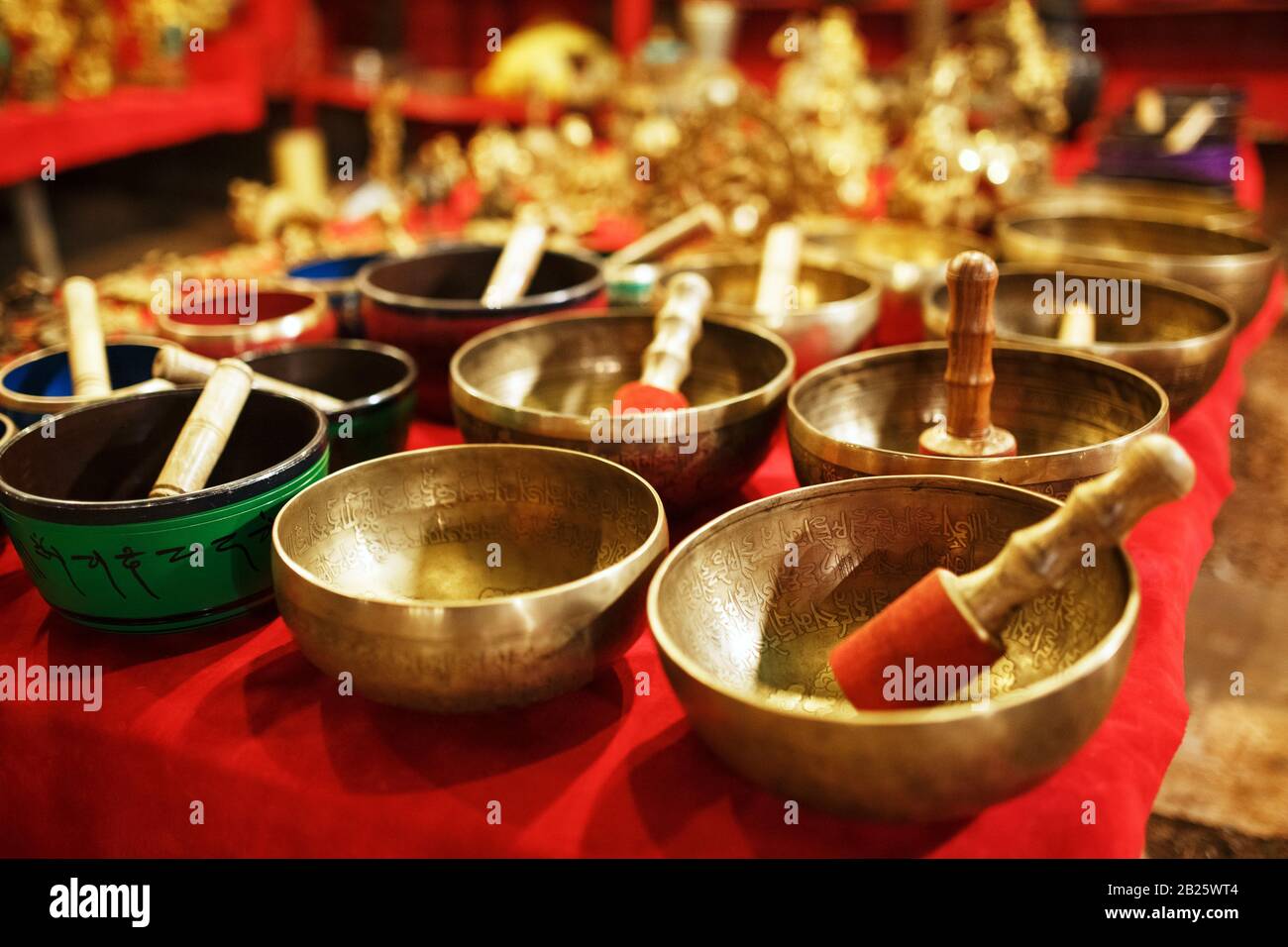 Golden Tibetan singing bowls on counters with red cloth of the night market Goa India Stock