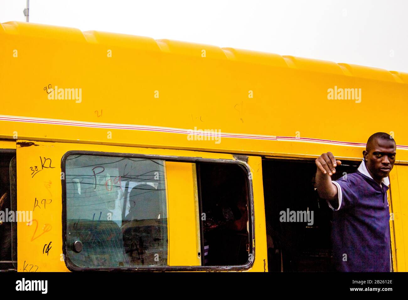 A danfo bus conductor calls out to passengers on a street in Lagos, Nigeria. Stock Photo