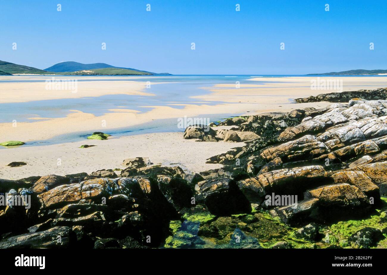 Rocky shoreline and sands of Luskentyre (Losgaintir) Beach on a beautiful Summer day in June with blue sky, Isle of Harris, Scotland, UK Stock Photo