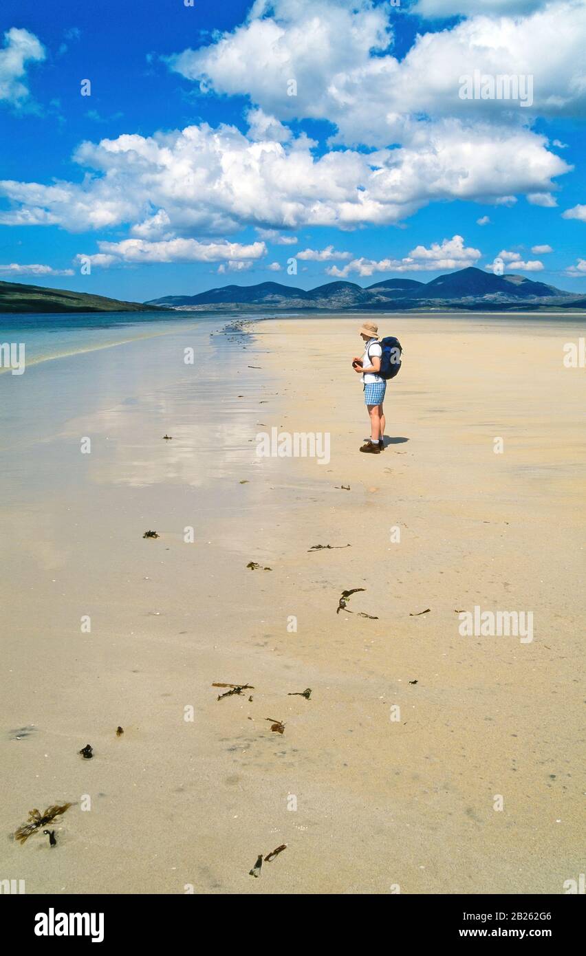 Lone walker on empty sands of Luskentyre (Losgaintir) Beach on a beautiful Summer day in June with blue sky, Isle of Harris, Scotland, UK Stock Photo