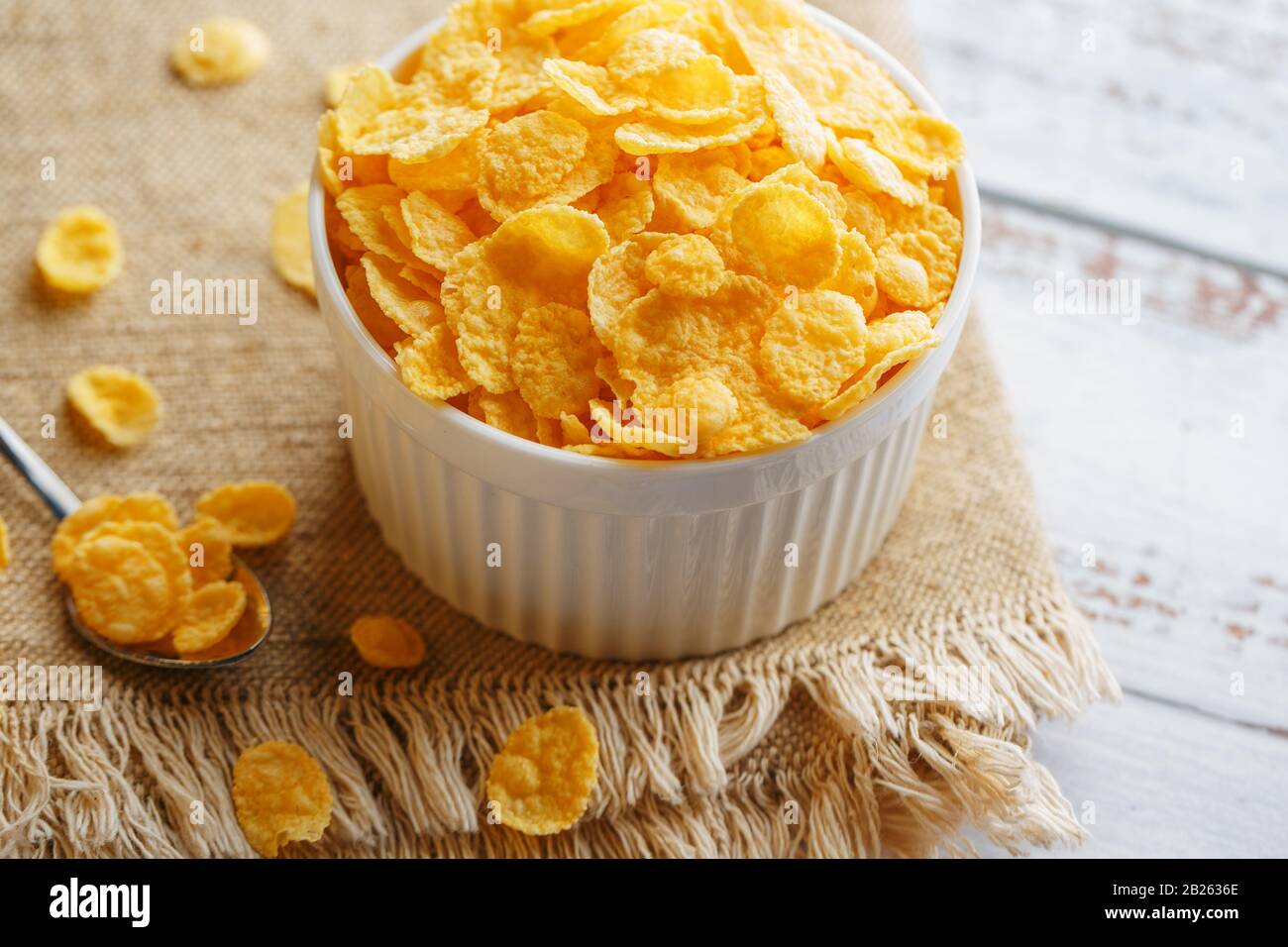 Bowl with golden flakes on a linen, on a light wooden table, next to a ...