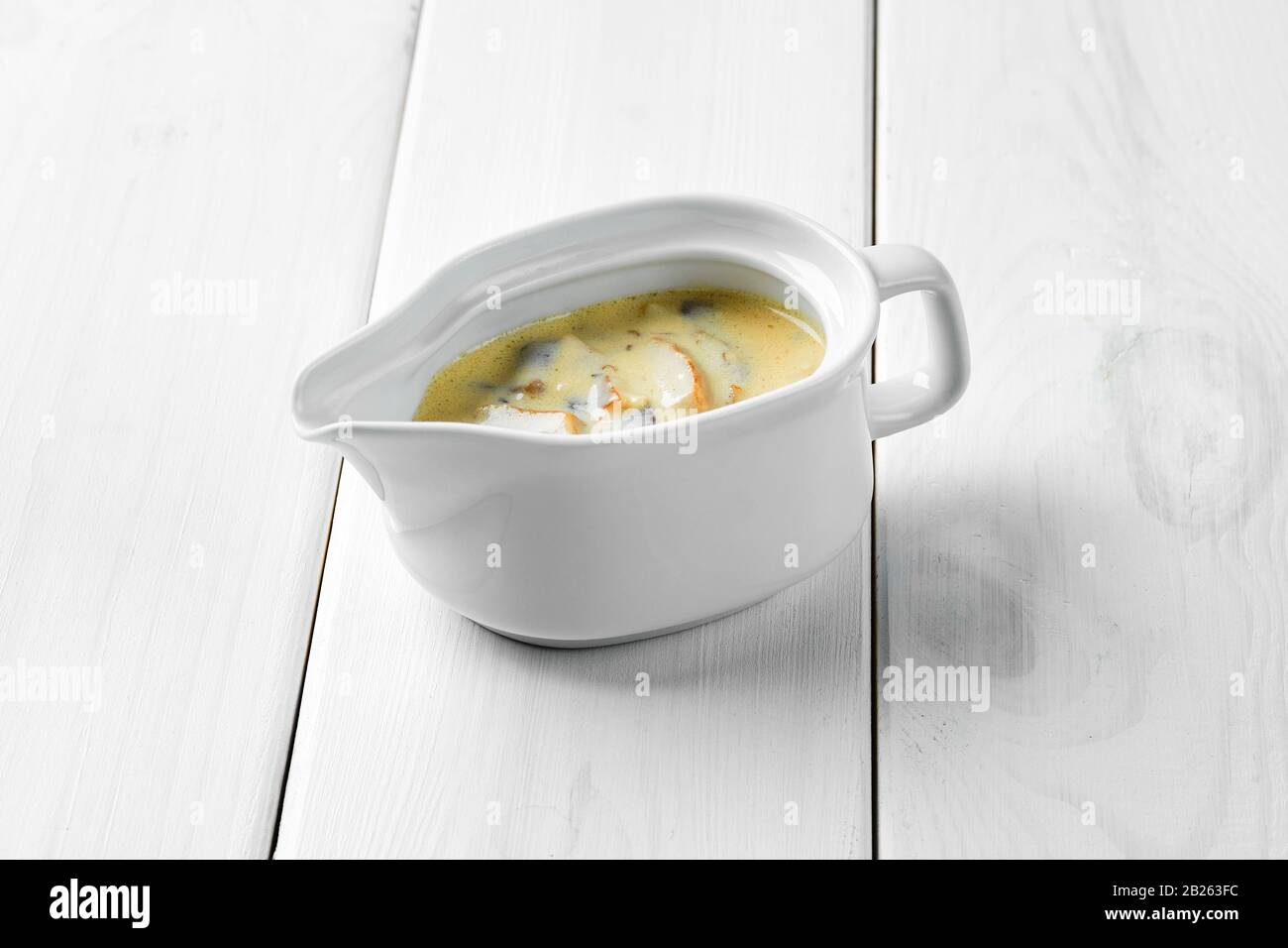 Mushroom sauce in ceramic gravy boat on white wooden table Stock Photo