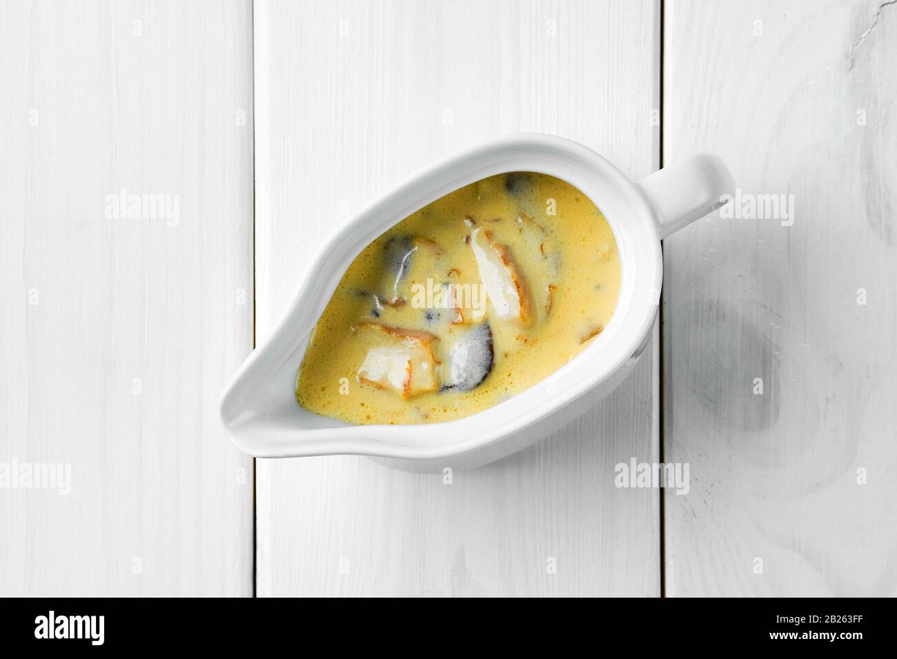 Mushroom sauce in ceramic gravy boat on white wooden table Stock Photo