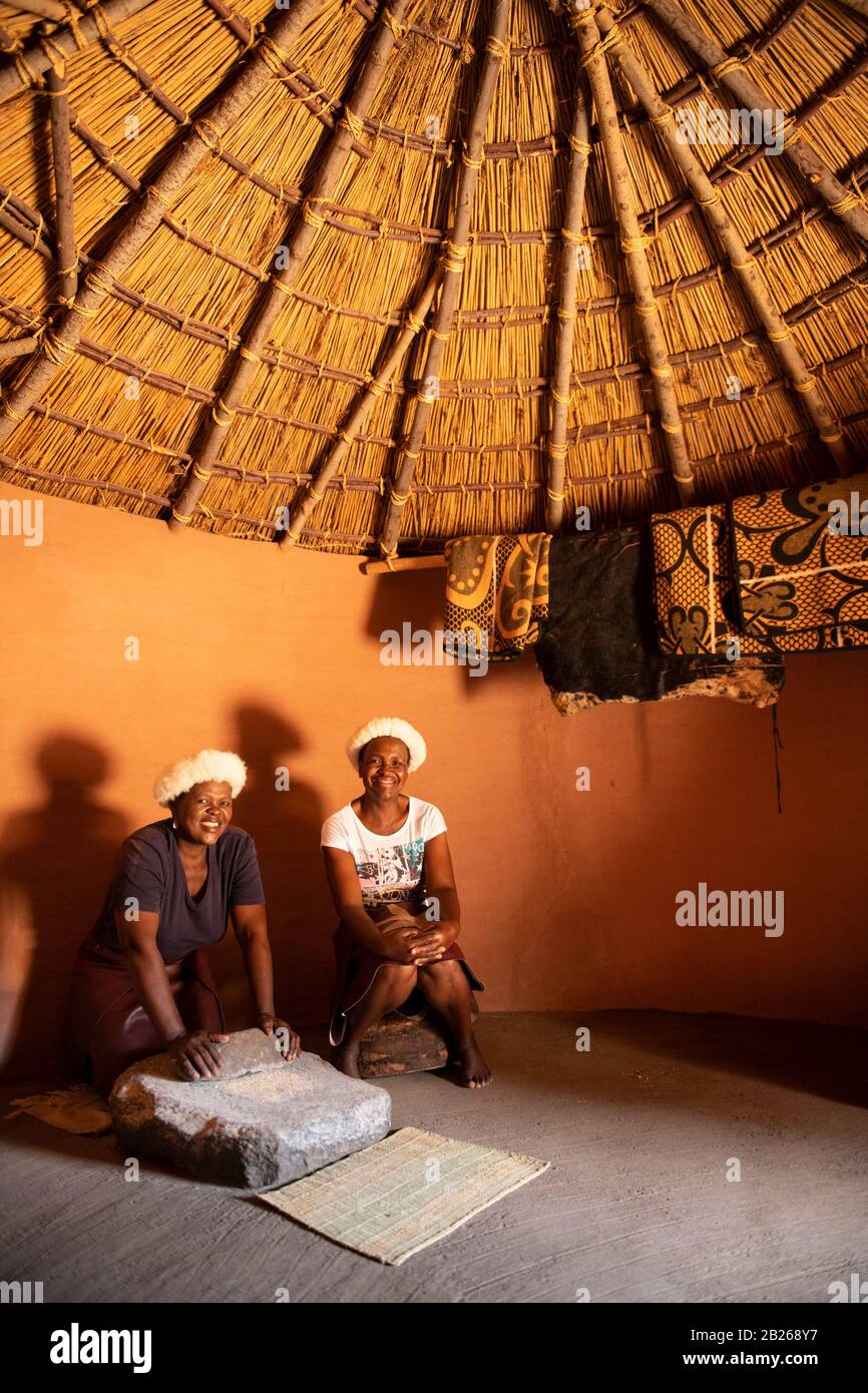 Basotho woman grinding maize in a traditional hut, Thaba Bosiu Cultural
