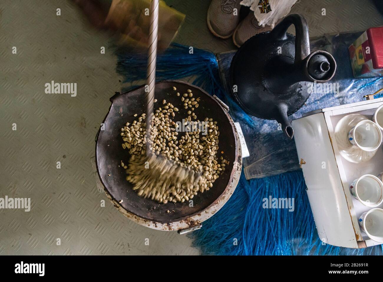 Roasting of green immature coffee beans on a flat pan in a house in southern Ethiopia Stock Photo