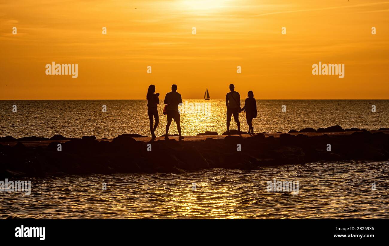silhouette of people walking and biking on the pier during the golden ...