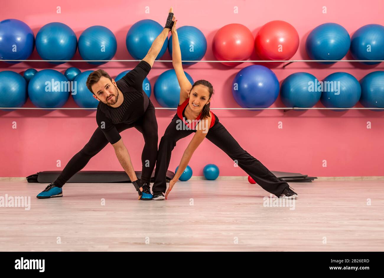Young couple doing stretching exercises in a gym Stock Photo - Alamy
