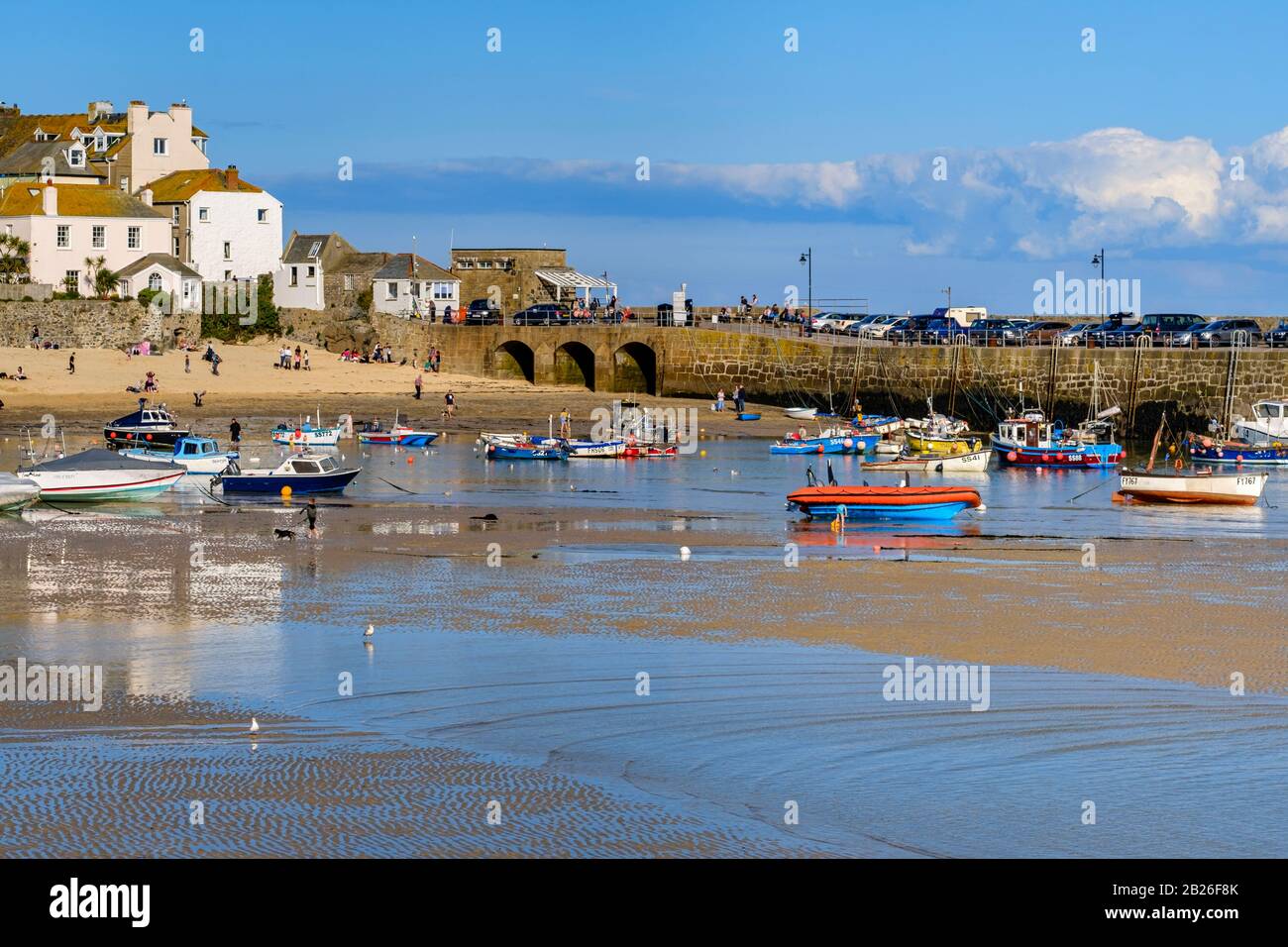 Harbour beach to the Harbour at St Ives with houses and Smeatons Pier in the distance, people on the beach and fishing boats moored ,Cornwall, S West Stock Photo