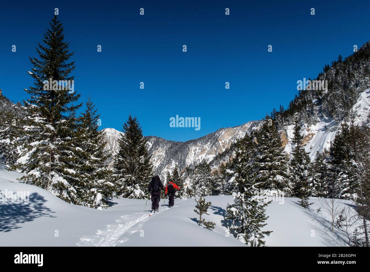 Two men ski tour through the Vallée des Avals near the French alpine resort of Courchevel after fresh snowfall on a sunny day. Stock Photo