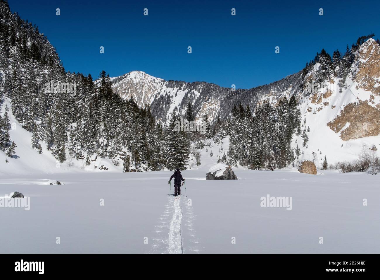 A man ski tours through the Vallée des Avals near the French alpine resort of Courchevel after fresh snowfall on a sunny day. Stock Photo