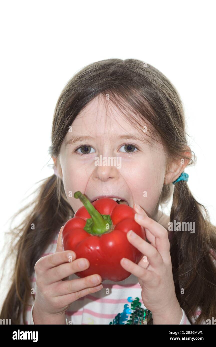 young girl eating a red bell pepper whole Stock Photo