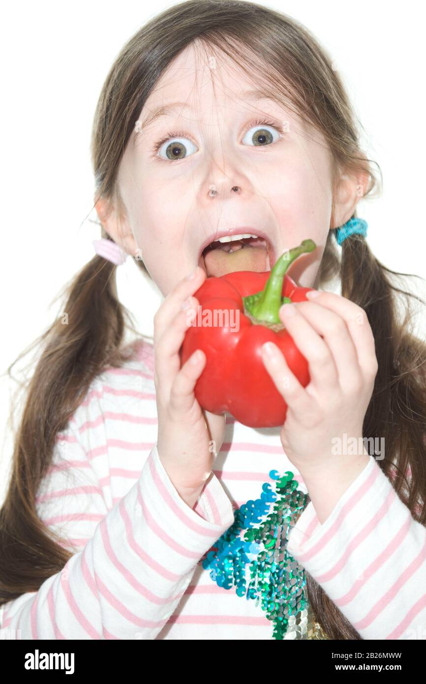 6 year old girl about to eat a whole red bell pepper Stock Photo