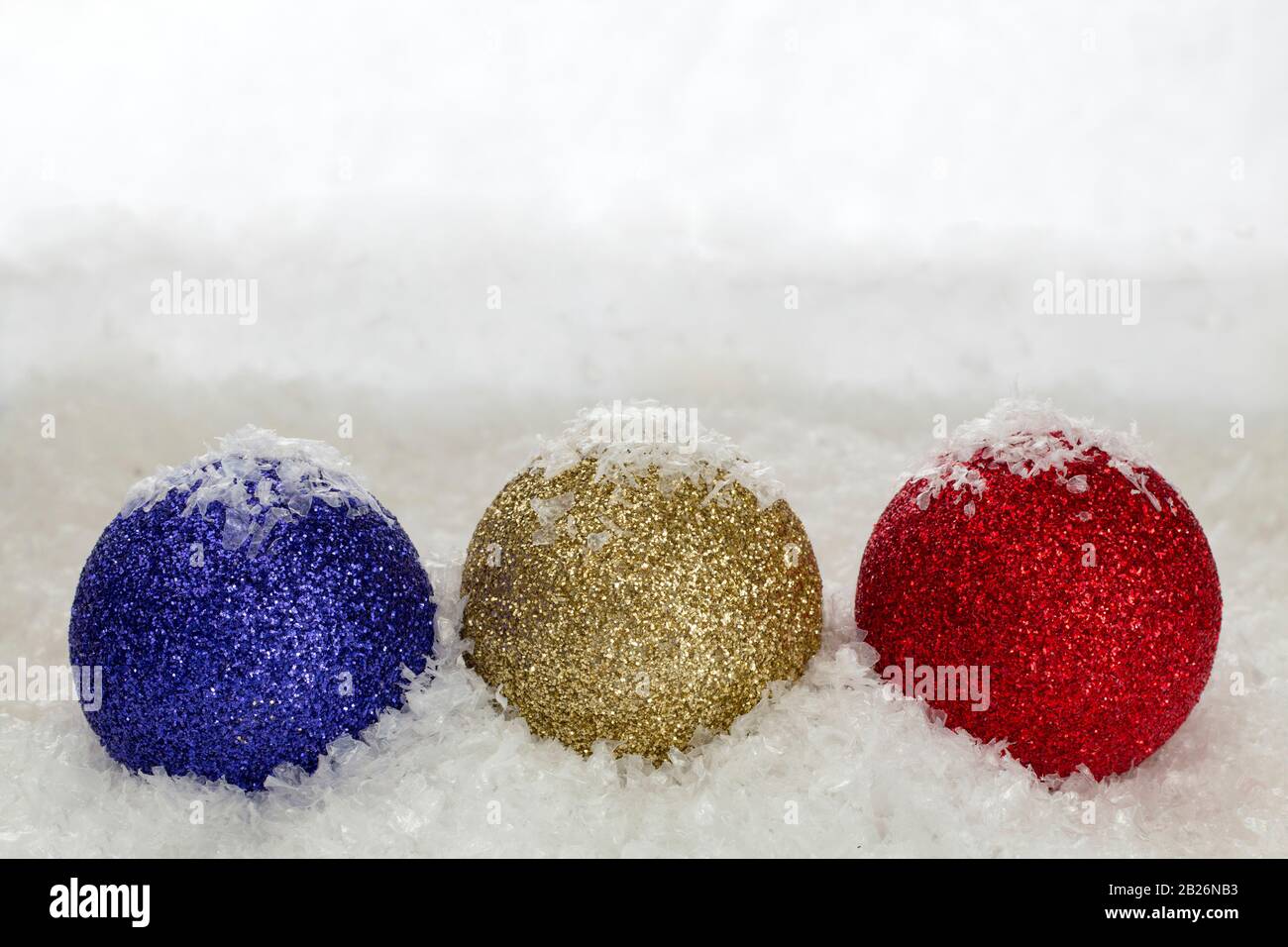 Christmas baubles sprinkled with snowflakes against a snow backdrop with copy space Stock Photo