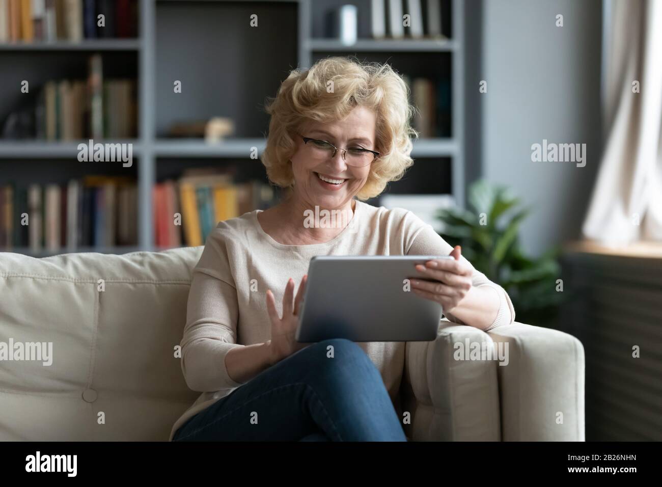 Middle-aged woman using tablet gadget at home Stock Photo