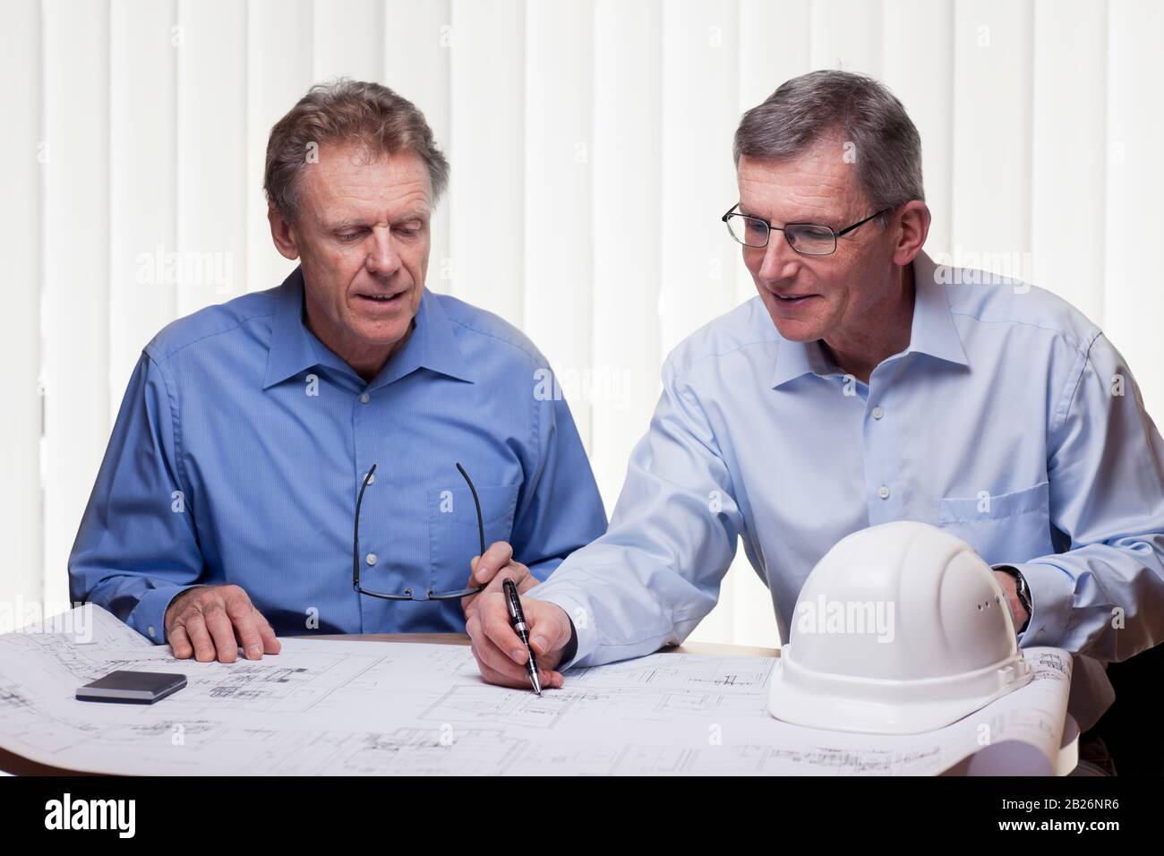 Two mature architects or engineers discussing a construction plan in a bright office Stock Photo