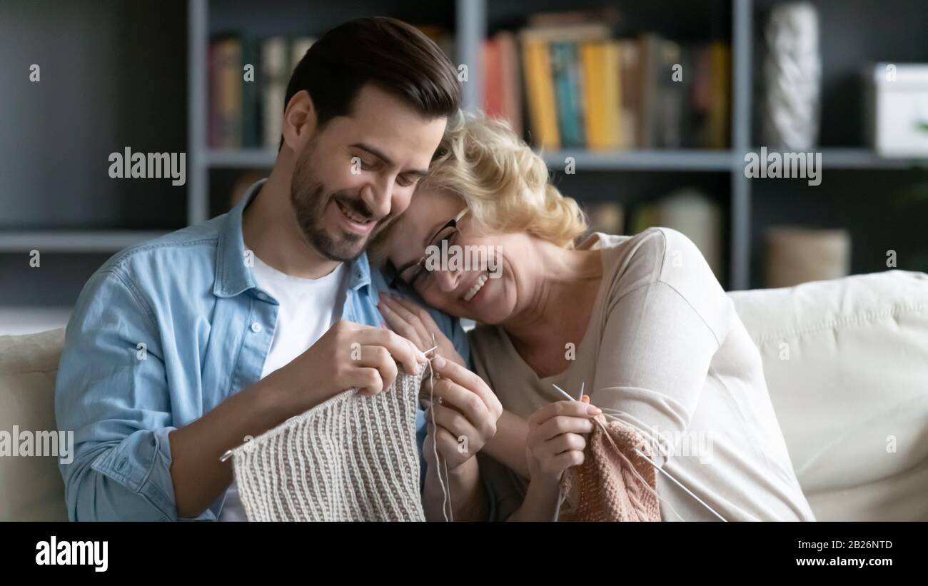 Smiling mature mom and adult son knitting together Stock Photo