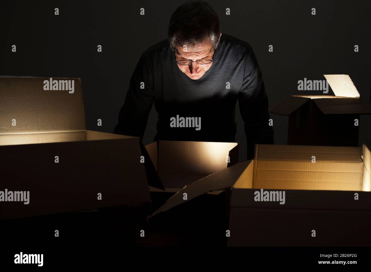 Mature curious man opening parcels with lights inside Stock Photo