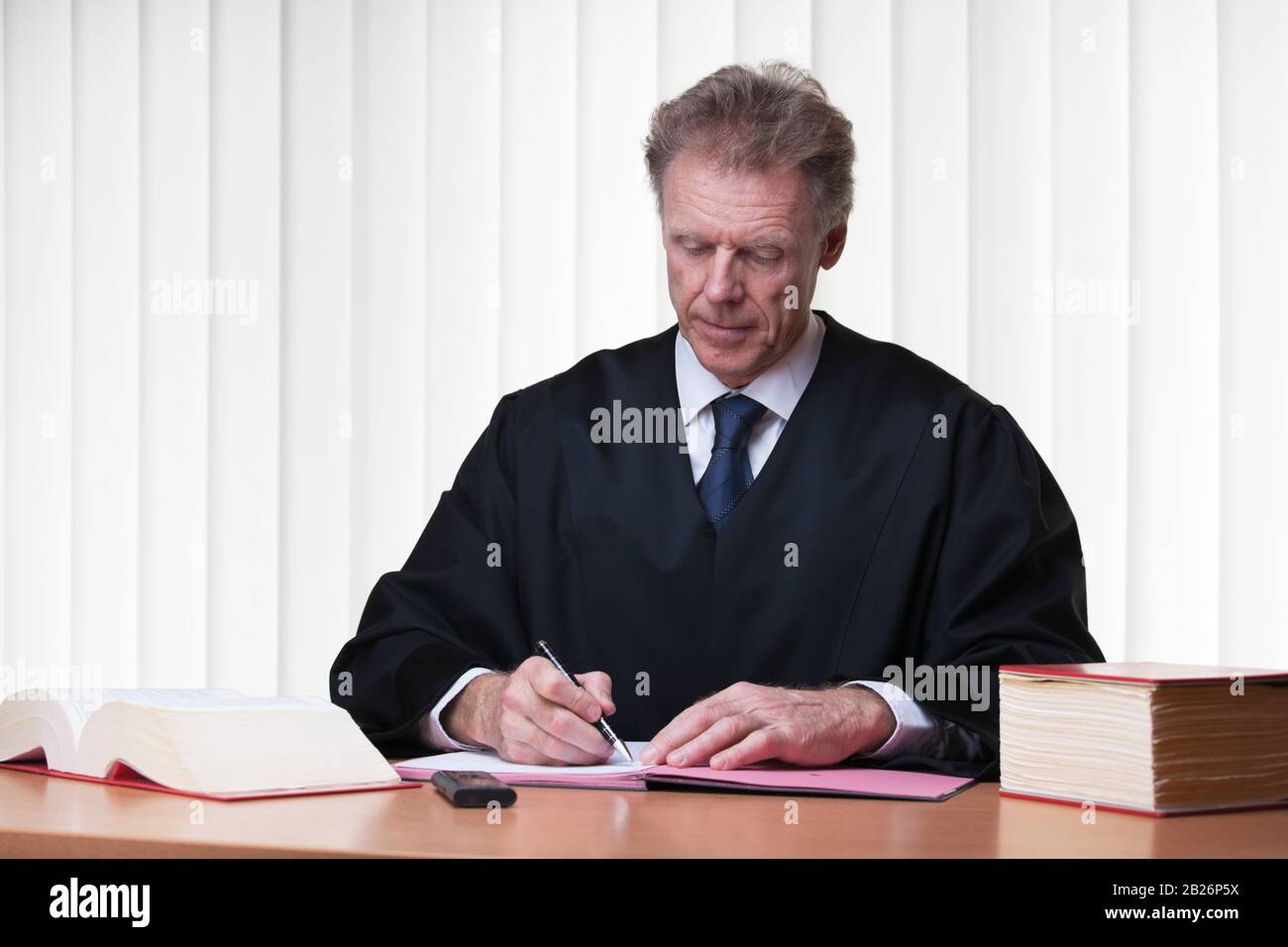 Judge or lawyer writing at his desk in a bright courtroom Stock Photo