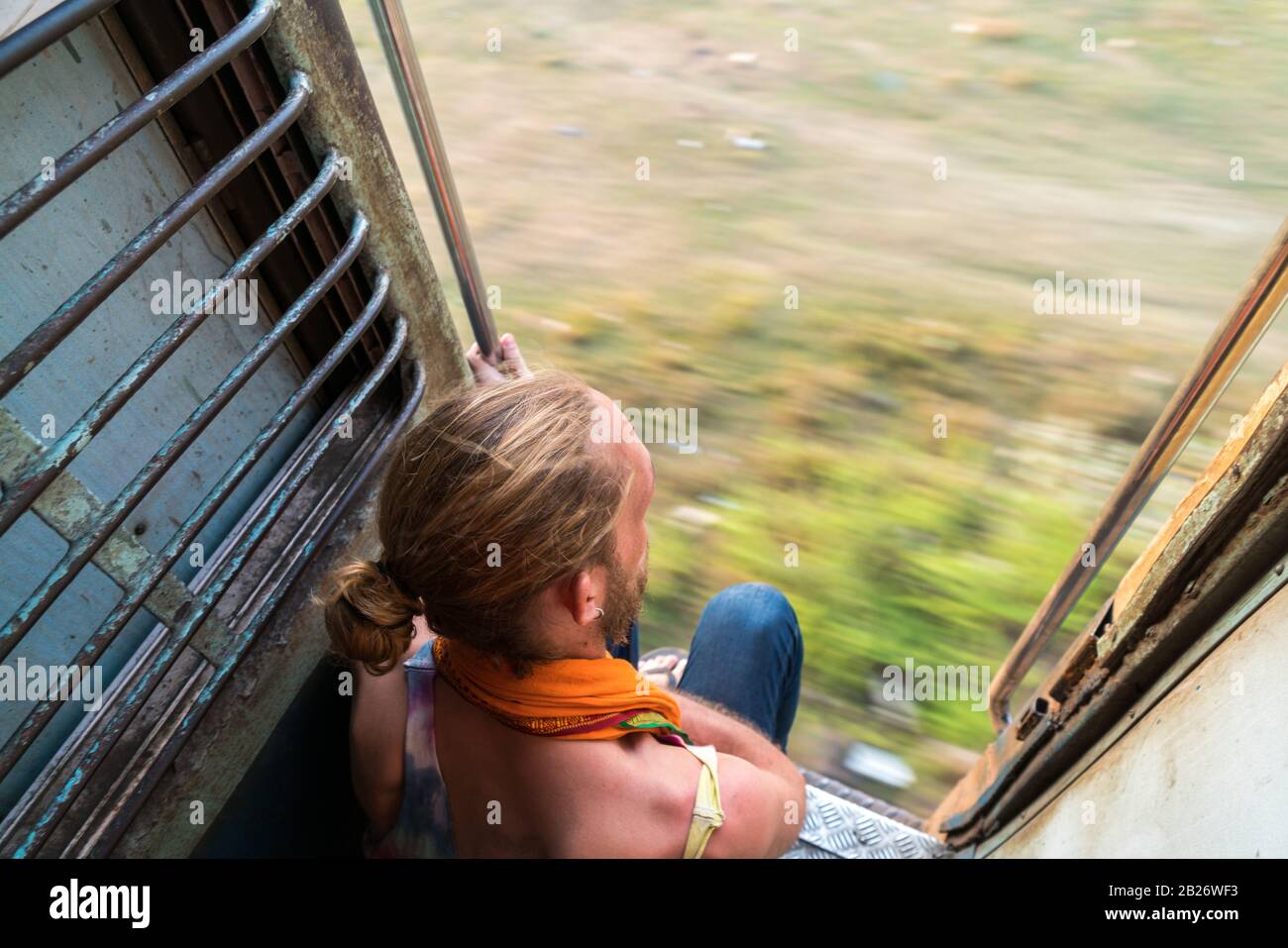 Male backpacker traveler riding an open train in India Stock Photo