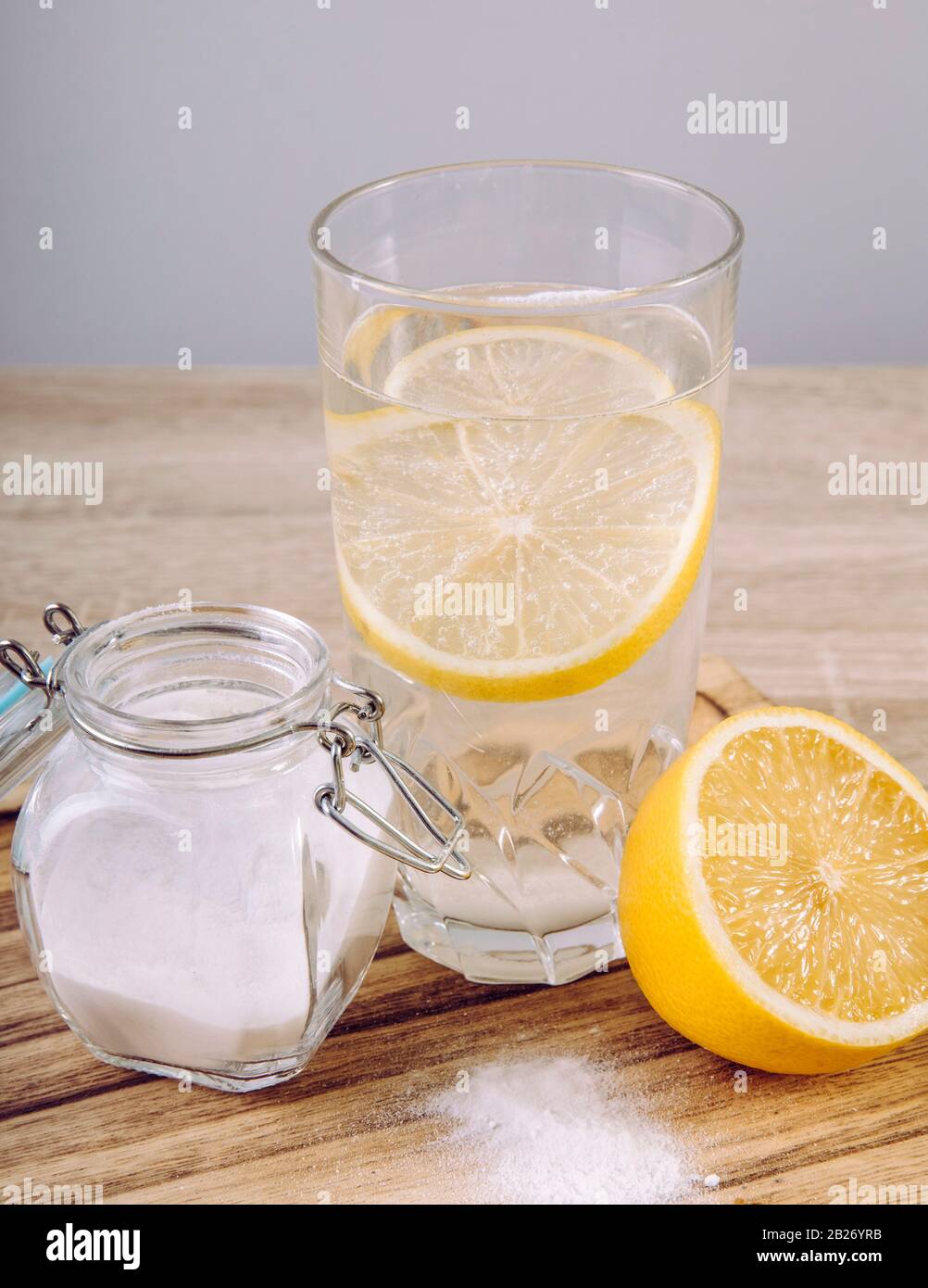 Baking soda in drinking glass with water and lemon juice, health benefits for digestive system concept on natural wooden background. Stock Photo