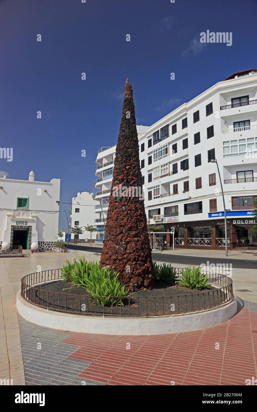 Conical sculpture made from pieces of lava rock, with Open University building (UNED) on left, Avenida La Marina, Arrecife, Lanzarote Stock Photo