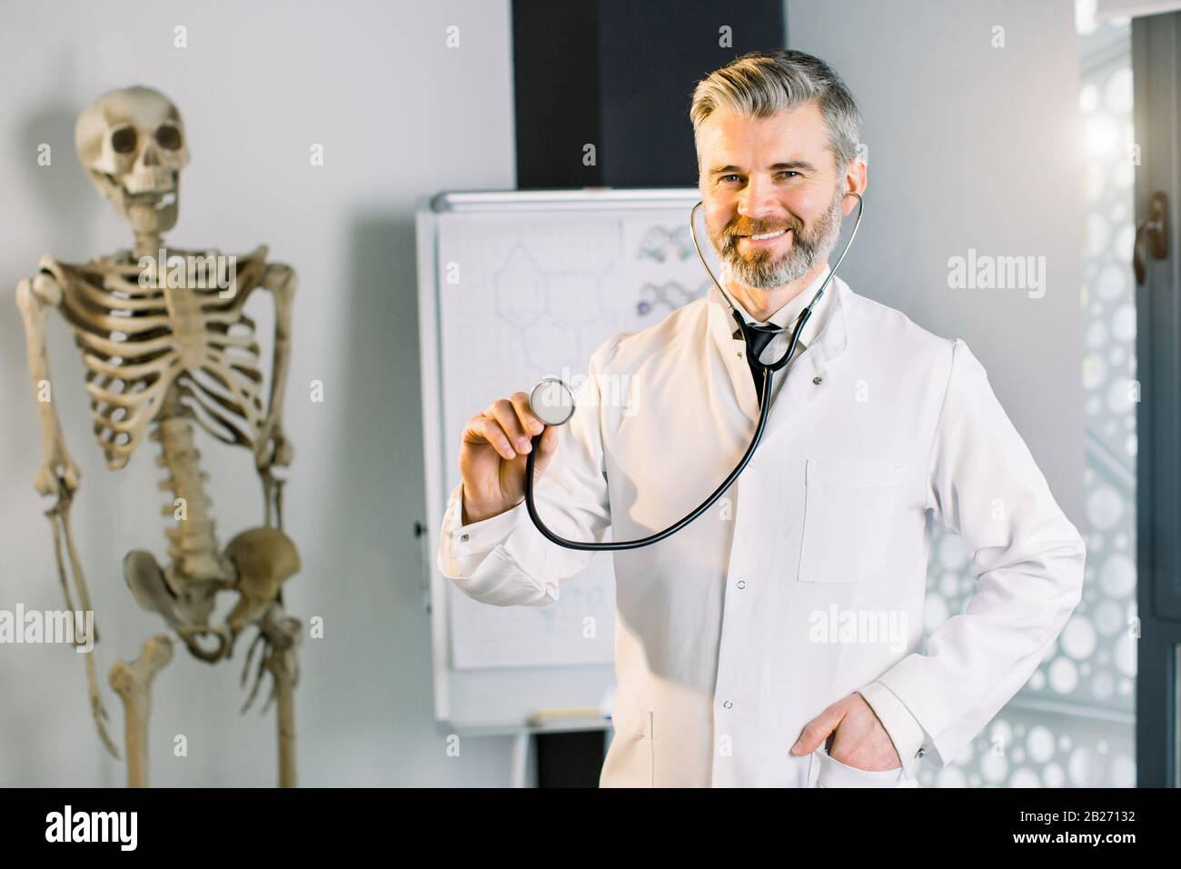 Male smiling doctor showing stethoscope for checkup to auscultate