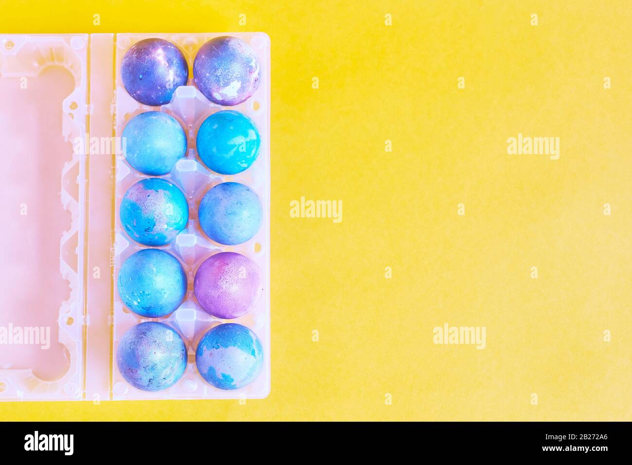 Painted Easter eggs with space intergalactic pattern in stand on yellow background Stock Photo